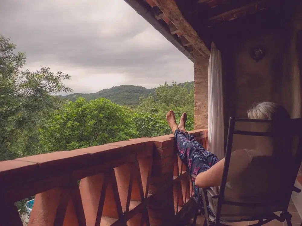 Huésped relajándose en terraza de casa rural con vistas a la montaña en Cataluña, fotografía lifestyle
